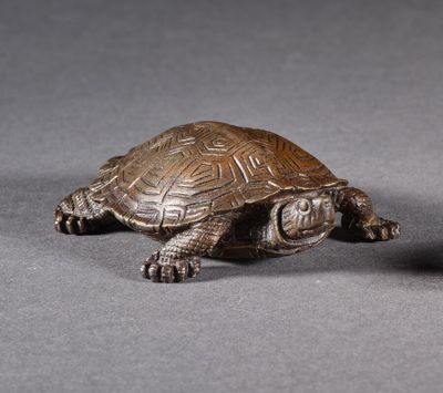 figurine en bronze représentant une tortue et une balle sur un fond gris