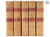 four old books are lined up in a row on a white surface