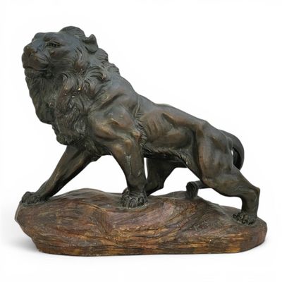 bronze statue of a lion on a rock on a white background