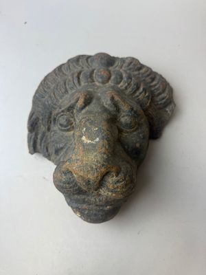 une statue représentant une tête de lion sur un fond blanc
