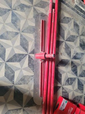 un radiateur rouge posé sur un sol carrelé, à côté d'un tuyau rouge