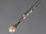 une photo d'un collier composé d'une perle blanche et d'un pendentif en argent, monté sur une chaîne en argent