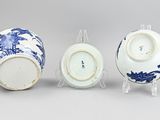 three blue and white vases and a bowl on a stand