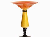 an orange glass vase with a black base on a white background