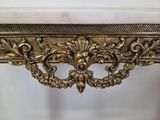 an ornate gold console table with a marble top