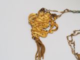 a gold necklace with a lion on it and a chain