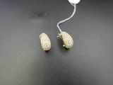 une paire de boucles d'oreilles pavées de couleur dorée sur un fond noir
