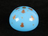 a blue ball with gold bugs on it on a black background