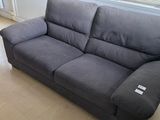 a grey couch sitting in a living room next to a window