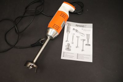 une perceuse électrique orange et blanche posée sur une table noire