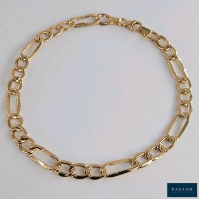 gros plan d'un bracelet en chaîne en or sur une surface blanche