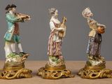 three figurines of people playing musical instruments on a table