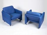 une paire de chaises bleues munies de roulettes et de repose-pieds, adossées à un mur blanc