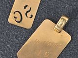 a close up of two gold tags with the letter s on them