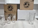 four glasses sitting on a table next to a box of beer