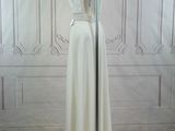 a white dress on a mannequin stand in front of a white wall