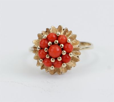 un gros plan d'une bague en or ornée de perles rouges