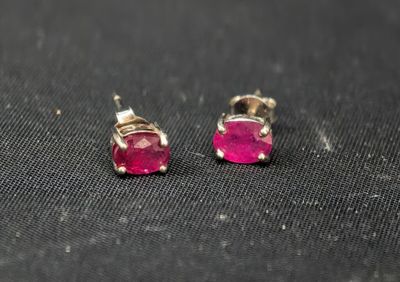 une paire de boucles d'oreilles à clous ornées de pierres roses sur un fond noir
