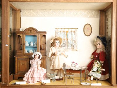 une maison de poupées avec des poupées dans une vitrine
