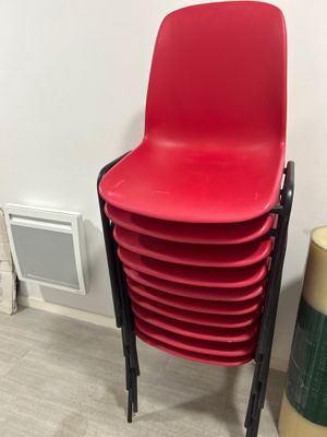 une pile de chaises en plastique rouges à côté d'une poubelle