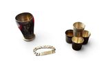 trois tasses et un bracelet posés sur une surface blanche