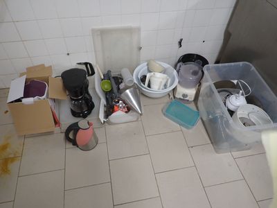 une photo d'une salle de bains où le sol est encombré d'objets
