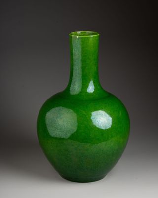 a green vase sitting on a table with a gray background