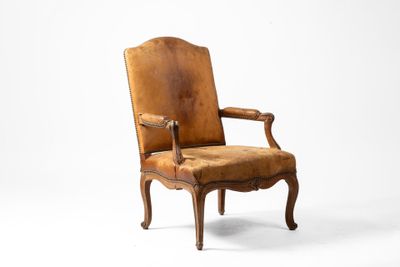 un vieux fauteuil dont le dossier et les accoudoirs sont recouverts de cuir marron