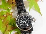 a black watch sitting on top of a leaf covered table