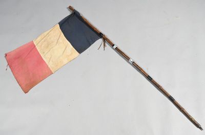 un vieux mât en bois surmonté d'un drapeau, posé sur une surface blanche