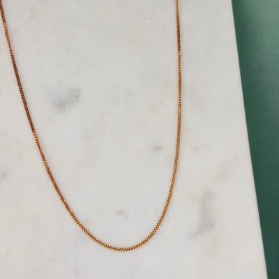 a gold chain necklace on a marble slab