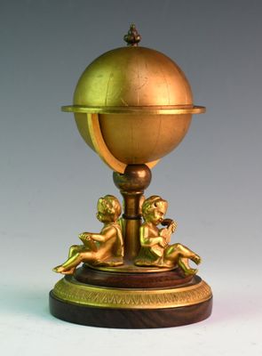 un globe doré posé sur un socle, orné de chérinsils