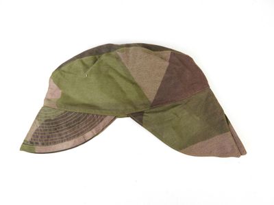 un chapeau vert et marron posé sur une surface blanche