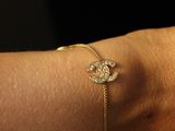 someone is wearing a gold bracelet with a diamond flower on it