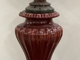 un vase rouge posé sur un tapis, à même le sol