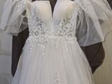 a white wedding dress hanging on a hanger in front of a white wall