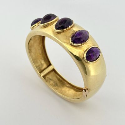 un gros plan d'une bague en or sertie de pierres violettes