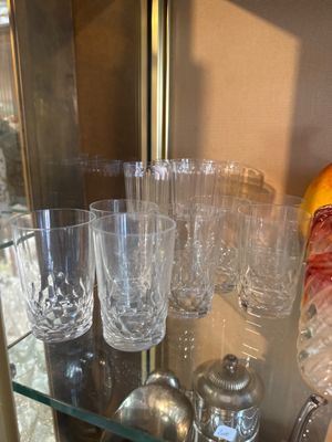 bottles and glasses on a glass shelf in front of a window