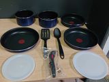 Plusieurs casseroles et ustensiles sont posés sur une table en bois