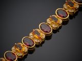 un gros plan sur un bracelet en or orné de pierres rouges et blanches