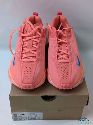 une paire de baskets Nike roses posées sur une boîte