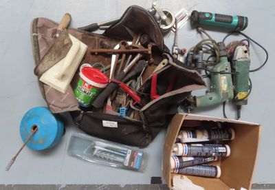 un sac rempli d'outils posé par terre à côté d'une paire de ciseaux
