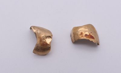 une paire de boucles d'oreilles en or sur une surface blanche