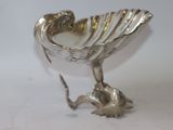 a silver shell shaped object on a white surface