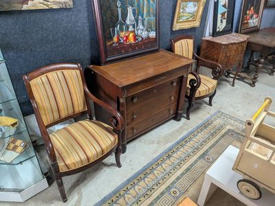 several chairs and a table in a room with paintings on the wall