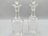 une paire de vases en verre transparent posés sur une surface blanche