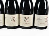 four bottles of wine are lined up on a white surface