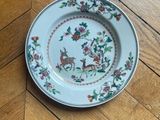 a plate with a deer and flowers on it on a wooden floor