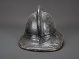 an old helmet is sitting on a table with a gray background
