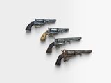 trois vieux revolvers sont alignés sur une surface blanche